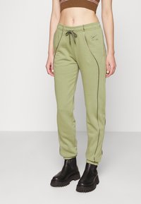 Gröna sweatpants med sidfickor, dragsko i midjan och kontrasterande sömmar. Klädd med svarta chunky ankelboots.