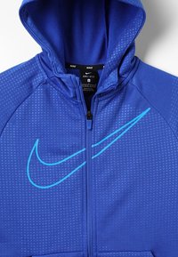 Felpa blu Nike Dri-FIT con chiusura con zip. Tessuto testurizzato con un motivo geometrico, grande logo Nike color teal e cappuccio.