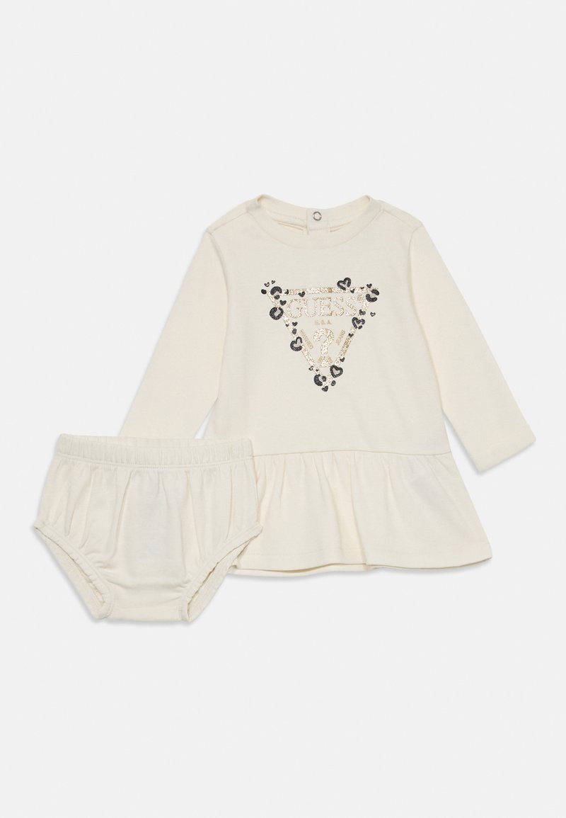 Robe crème à manches longues avec une taille peplum, dotée d'un design de logo triangulaire étincelant et d'accents léopard noirs, accompagnée de bloomers assortis.