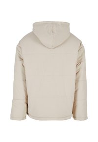 Beige vadderad jacka med huva, med en slät yta, rak skärning och horisontella sömmar över ryggen.