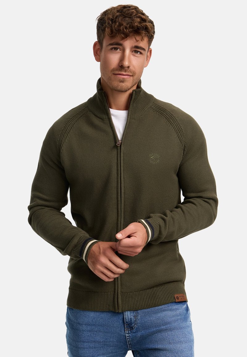 Olivengrønn zip-up genser med teksturert strikk, ribbestrikkede mansjetter med stripeaksenter, og et vevd merke i kanten. Fitted silhuett.