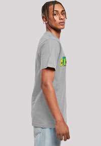 Gray cotton t-shirt featuring a colorful graphic design on the front. Short sleeves and a crew neckline. Styled with light denim jeans.