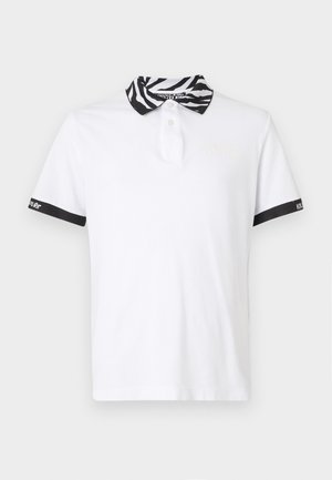 Biała koszulka polo z kołnierzykiem w czarno-białą zebraną szew. Posiada czarną lamówkę przy rękawach oraz wyszywane logo w jasnym kolorze.
