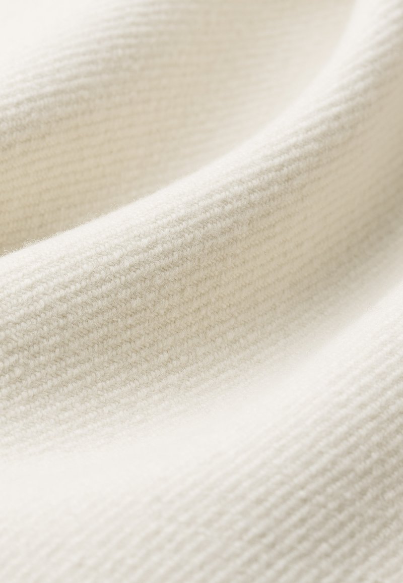 Tkanina bawełniana w kolorze off-white, charakteryzująca się prążkową teksturą oraz miękką i gładką powierzchnią. Fałdy i zagniecenia nadają głębię i wymiar.