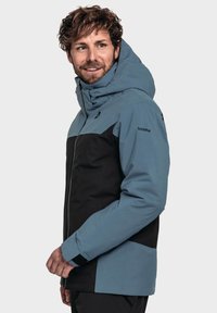 Herren Skijacke in Hellblau und Schwarz, mit hohem Kragen, abnehmbarer Kapuze, durchgehendem Reißverschluss und verstellbaren Bündchen. Wasserabweisendes Material.