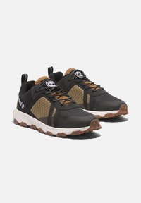 Zapatillas deportivas negras con parte superior de malla texturizada, acentos naranjas y suela de goma resistente. Cierre de cordones y lengüeta en el talón.