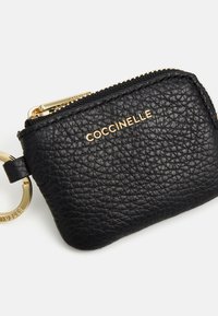 Portachiavi in pelle nera con finitura testurizzata, zip dorata e branding dorato. Forma rettangolare compatta con attacco per chiavi.