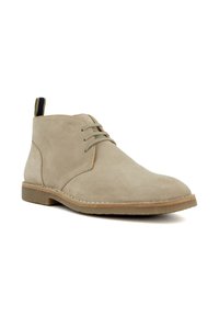 Light beige suede desert boot with three eyelets for laces, stitched sole, and black-and-beige fabric pull tab at the back.