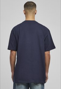 Tricou din bumbac de culoare bleumarin, cu mâneci scurte și croială dreaptă, având gât rotund și fără grafice sau modele vizibile.
