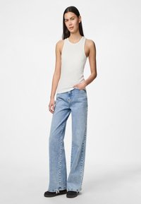Top de tirantes de canalé gris claro combinado con jeans anchos de corte azul claro, con un ajuste relajado ydo orilla deshilachada, completado con calzado negro.