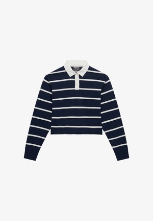 Marineblauw cropped poloshirt met lange mouwen, witte horizontale strepen en een witte kraag. Voorzien van een drieknopensluiting bij de hals.