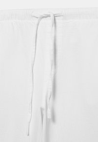 Pantalon en tissu blanc avec taille à cordon, cordons noués à l'avant et détail de taille élastique.