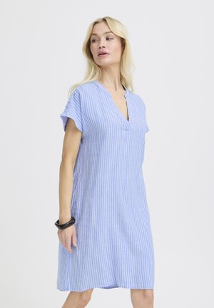 Donna che indossa un vestito al ginocchio a righe verticali azzurre e bianche, maniche corte e braccialetto nero, che guarda di lato.