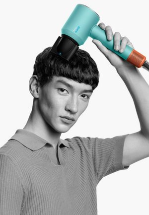 Een teal haardroger met een zwarte mondstuk en oranje accenten wordt boven het hoofd van een persoon gehouden. Ze dragen een gestructureerde, grijze poloshirt.