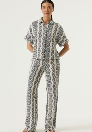 Hemd- en broekset van geweven stof met een golvend patroon in marineblauw en crème. Het hemd heeft korte mouwen en een sluiting met knopen aan de voorkant.