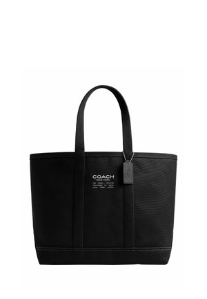 Čierna kabelka Coach New York typu tote s dvoma rukoväťami, biely potlačený logotyp vpredu a visiaca čierna visačka na bielom pozadí.