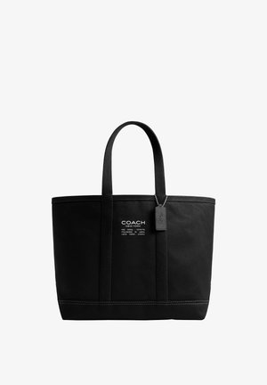 Čierna kabelka Coach New York typu tote s dvoma rukoväťami, biely potlačený logotyp vpredu a visiaca čierna visačka na bielom pozadí.