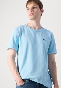 Φωτεινό μπλε T-shirt κοντό μανίκι από βαμβάκι, με στρογγυλή λαιμόκοψη, αντίθετες ριπές στους μανίκους και μικρό μαύρο λογότυπο.