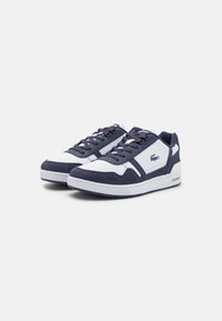 Sneaker navy e bianche realizzate in materiali scamosciati e sintetici, con un design elegante, punta testurizzata e dettaglio del logo sul lato.