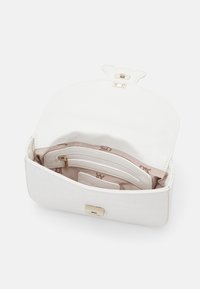 Borsa a tracolla bianca in materiale goffrato a motivo coccodrillo con una chiusura dorata, dotata di un interno rosa e diversi scomparti per l'organizzazione.