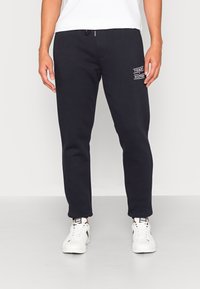 Navy sweatpants met een elastische tailleband, taps toelopende benen en een logopatch. Gemaakt van zachte stof met een geborstelde textuur.