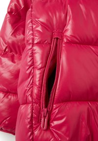 Veste rembourrée rose vif avec des panneaux matelassés brillants. Équipée d'une poche zippée avec un zip assorti et d'une texture lisse.