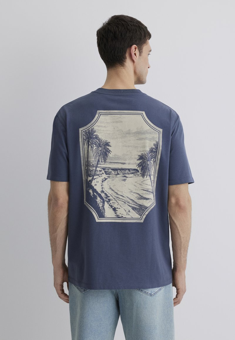 Navy blue cotton t-shirt featuring a large vintage beach scene print with palm trees on the back, short sleeves, and a relaxed fit.