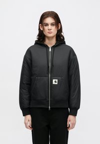 Schwarze isolierte Bomberjacke mit Kapuze, ausgestattet mit einem Frontreißverschluss, zwei Taschen, gerippten Bündchen und Saum sowie einem quadratischen Logopatch auf der Brust.