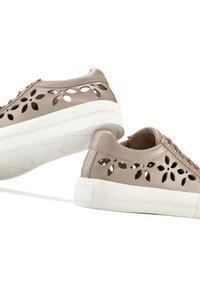 Beige leather sneakers with cut-out floral pattern, white textured sole, and round laces. The design features a smooth finish and low profile.