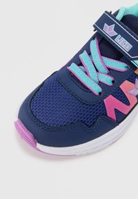 Marinefarbene Sportschuh ausMesh-Material, mit lila Akzenten und türkisfarbenen Schnürsenkeln. Verfügt über einen Klettverschluss und eine strukturierte Sohle für besseren Halt.