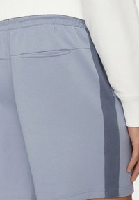 Pantalones cortos de color azul claro con un panel lateral texturizado, cintura elástica y un bolsillo trasero. Hechos de una tela suave y elástica.