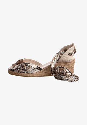 Chaussure espadrille à semelle compensée avec un dessus en tissu marron à motifs, des accents beiges et une semelle en jute, maintenue par une sangle décorative.