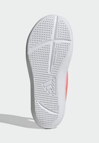 Suola di scarpa con superficie in gomma bianca texturizzata, dotata di perforazioni per migliorare la presa e un logo in rilievo. I bordi curvi migliorano la flessibilità.