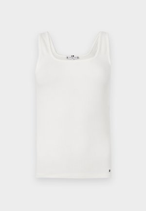 Canottiera bianca a costine con spalline larghe e scollatura a forma di cuore. Presenta cuciture sottili lungo i bordi e un accento di marca nella parte inferiore.