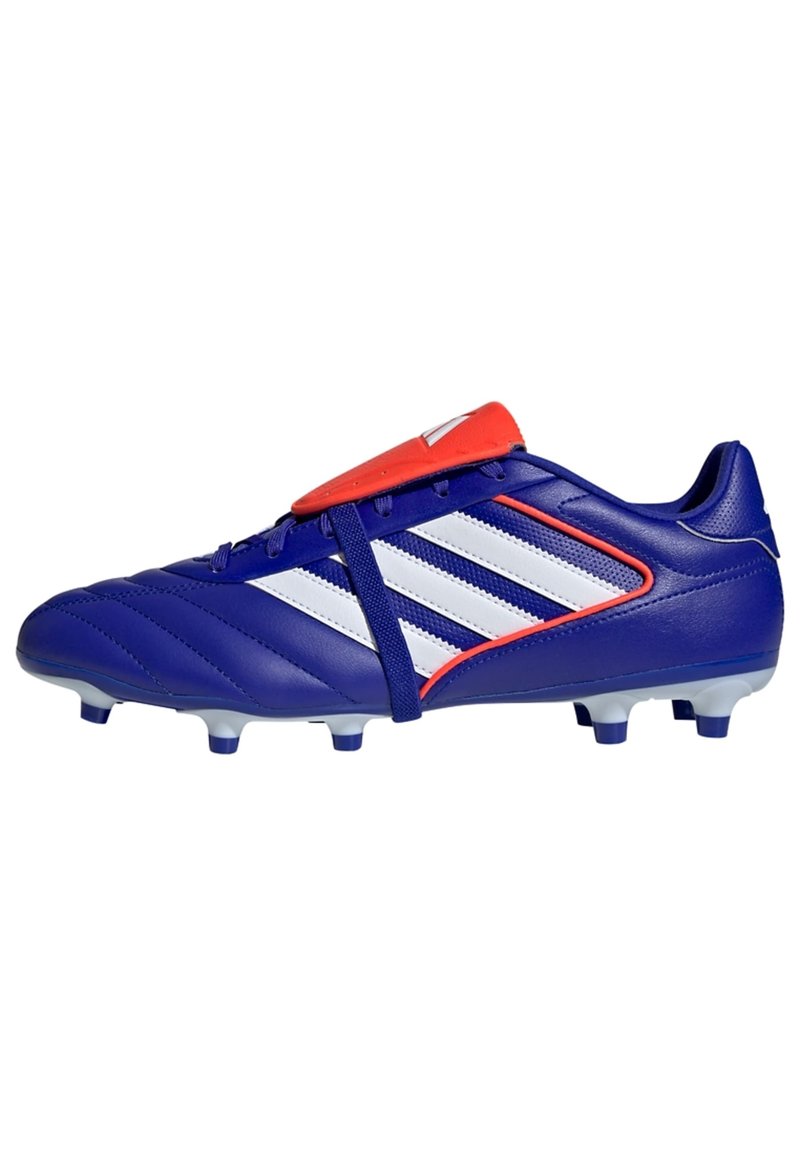 Botas de fútbol azules con una parte superior sintética texturizada, rayas blancas, acentos rojos y tacos moldeados para tracción en césped artificial o natural.