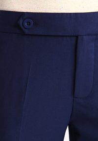 Mörkblå byxor i en slät tygkvalitet, med enstaka knappstängning och en framficka med subtila sömdetaljer.