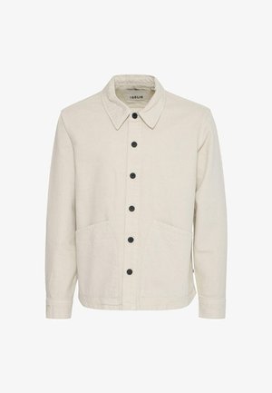 Veste en coton beige avec un col structuré, une fermeture avant à boutons, deux grandes poches et des boutons noirs pour le contraste.