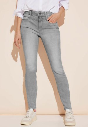 Grey slim-fit jeans made of denim, with a simple design, front pockets, and a button closure. Paired with white sneakers.