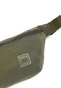 Olivovo zelená bedrová taška vyrobená z odolnej látky, s uzatváraním na zips a textúrovanou plastovou nášivkou s logom. Pripojený nastaviteľný pás.