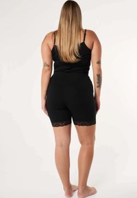 Zwarte shorts met een kantafwerking aan de onderkant, gecombineerd met een zwart tanktop. De stof lijkt glad en heeft een aansluitend ontwerp.