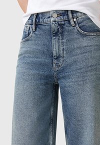Jeans in denim azzurro chiaro con vita alta, dotati di un classico design a cinque tasche, cuciture visibili e chiusura con bottone metallico.