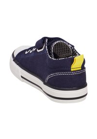 Baskets en toile bleu marine avec semelle en caoutchouc blanc, bandes noires et onglet au talon jaune. Dotées d'une doublure intérieure texturée et de coutures blanches.