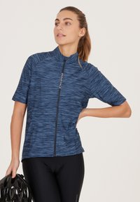 Blå cykeltröja med korta ärmar, texturerad, lättviktstyg, dragkedja fram och slim fit, i kombination med svarta vadderade shorts och en hjälm.