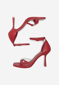 Sandali con tacco alto in pelle rossa, dotati di due sottili cinturini alla caviglia, design con punta quadrata e elegante tacco a stiletto. Texture liscia, dettagli minimi.