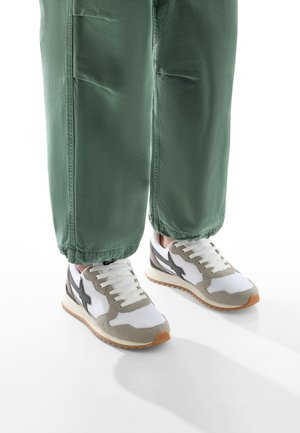 Zapatillas con una combinación de colores blanco, gris y negro; materiales de ante y malla; punta redonda; que cuentan con cordones y una suela de goma.