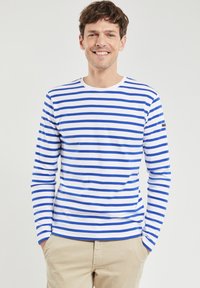Langærmet skjorte med vandrette blå og hvide striber, rund halsudskæring, lavet af blødt stof, med et logo på venstre ærme.