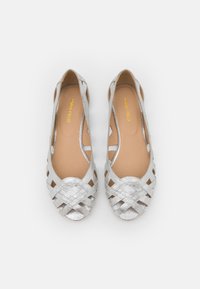 Zapatos planos metálicos plateados trenzados para mujer con diseño de punta abierta y plantillas acolchadas en tono marrón, etiquetados como "Anna Field", sobre un fondo blanco.