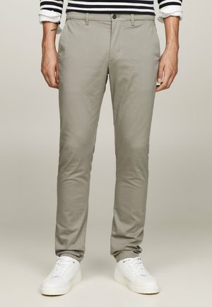 Pantaloni grigi chiari realizzati in tessuto intrecciato, con una vestibilità slim, tasche frontali e chiusura con un solo bottone. Abbinati a sneaker bianche.