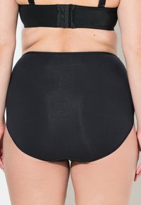 Zwarte high-waisted ondergoed, gemaakt van gladde stof, met een naadloos design en een lichte glans, met een afgeronde achterkant.