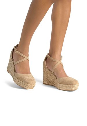 Chaussures à talons compensés en suede beige avec une plateforme en jute tressé. Elles présentent des brides croisées à la cheville et un design à bout rond.